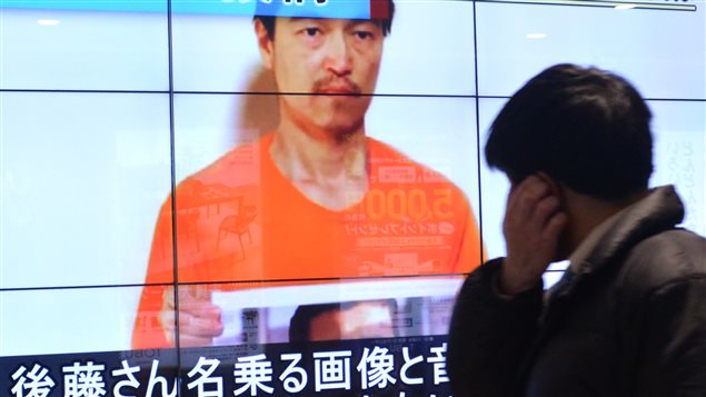 رجل يقف أمام شاشة تلفاز في أحد شوارع طوكيو يوم الأربعاء الفائت يُعرَض عليها شريط فيديو لتنظيم "الدولة الإسلامية" يظهر فيه الصحافي الياباني المخطوف كنجي غوتو  