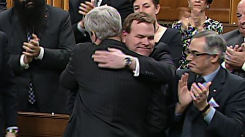 John Baird reçoit l'accolade du premier ministre Harper après l'annonce de son départ de la vue publique.