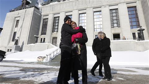Lee Carter et son mari Hollis Johnson s’enlacent devant le bâtiment de la Cour suprême, à Ottawa, à la suite du jugement de la Cour suprême sur le suicide assisté, le 6 février.