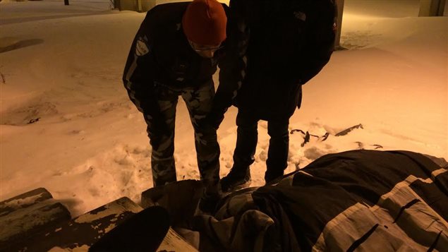 Un agent du Service de police de la Ville de Montréal (SPVM) et un éducateur spécialisé tentent de convaincre un homme itinérant de se mettre à l’abri du froid au parc Viger à Montréal, en février 2015.