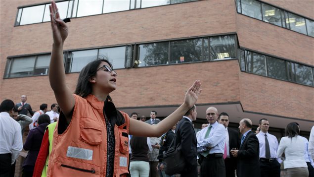Mujer dirige a la gente que evacúa los edificios en Bogotá, después del temblor de ayer martes 10 de marzo. 