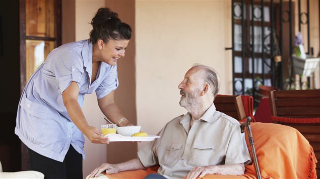 Une femme sert un repas à un homme en perte d'autonomie. Une femme sert un repas à un homme en perte d'autonomie.