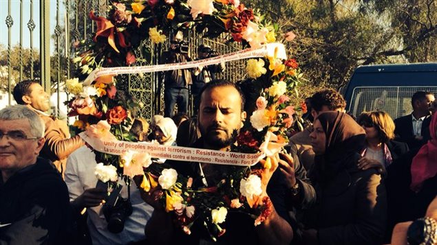 Un homme porte une couronne de fleurs à la mémoire des victimes de l'attentat contre le musée du Bardo.