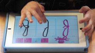 Un enfant apprend l’alphabet avec une tablette.