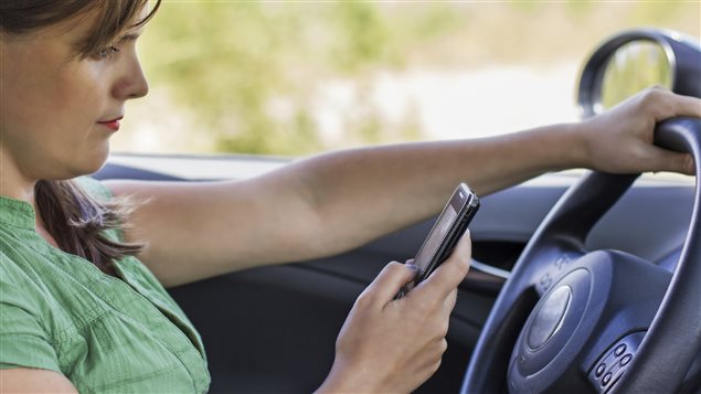 Une femme envoie un message texte en conduisant. Une femme envoie un message texte en conduisant.
