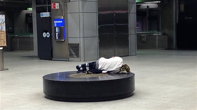 Un sans-abri, seul au milieu de la station de métyro Berri-UQAM dans la ville de Montréal.