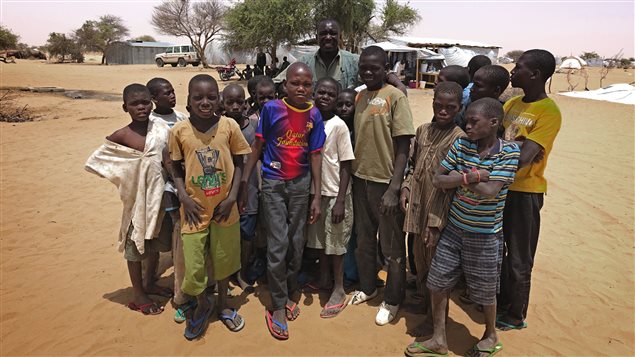 Idriss Dezeh, le gérant du camp de réfugiés de Dar es Salam, entouré d'enfants