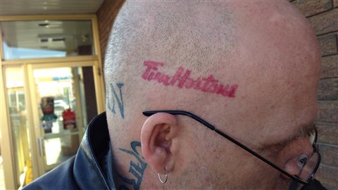 Un Canadien arbore un tatouage du logo de la chaîne de cafés Tim Hortons sur sa tête.