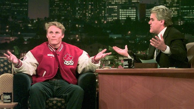 Ross Rebagliati was at the height of his fame when he appeared with NBC Tonight Show host Jay Leno, left, in the winter of 1998. Rebagliati, wearing his red and white Team Canada jacket and jeans, sits in the guest chair next to Leno's desk. Leno is wearing a suit and tie and looking at Rebagliati, who is gesturing with both arms wide and looking at the audience. Leno, too