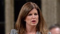 Rona Ambrose is not happy with Vancouver's move to regulate dispensaries. We see her from the neck up speaking the Commons. She has shoulder length auburn hair, parted at the left. She appears to be both thinking and talking at the same time. Her mouth is slightly agape.