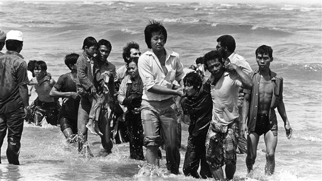 Des réfugiés vietnamiens arrivent sur les côtes de la Malaisie après le naufrage de leur bateau à quelques mètres au large. Photo prise à la fin des années 70, après la chute de Saigon.