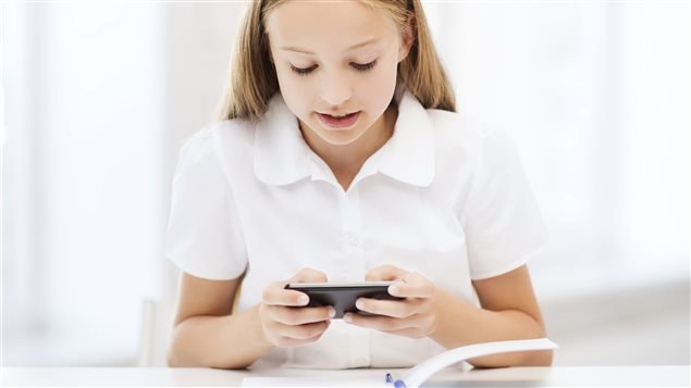 Une jeune fille écrit un texto lorsqu'elle fait ses devoirs.