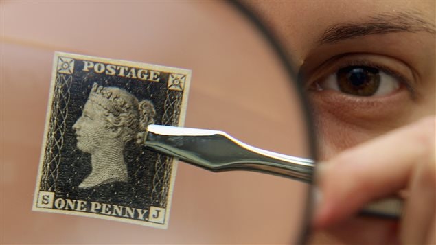 Un homme tient un timbre Penny Black à l'effigie de la reine Victoria, un des plus vieux timbres de l'histoire.