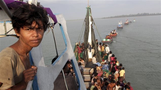 Un barco de pesca que transportaba migrantes rohingyas y bengalíes, es jalado hacia la orilla por pescadores.