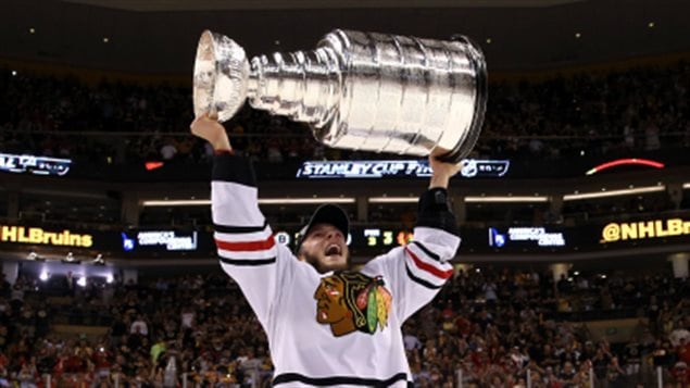 Captain Jonathan Toews (above) hopes to repeat Chicago's 2013 Stanley Cup victory over Boston this year against Tampa Bay. We see Toews dressed in the Hawks' white away sweater with the famed Indian head logo standing in the middle of the rink hoisting the Stanley Cup in triumph over his head.
