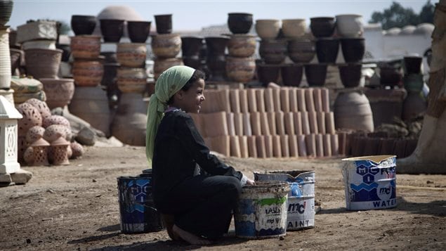 An Egyptian girl fills water containers at a pottery workshop in Cairo, Egypt. She is one of an estimated  168 million children who work.