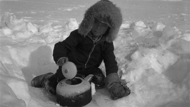 Petit garçon qui cherche de l’eau à l’aide d’une bouilloire à Brochet au Manitoba