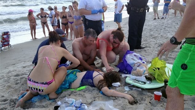 Miembros de los servicios de urgencia y varios bañistas ofrecieron ayuda a la joven víctima de un ataque de tiburón en Carolina del Norte.