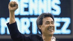 Dennis Martinez, author of a perfect game in 1991, was honoured during a ceremony for the Montreal Expos Hall of Fame in Montreal in 2004. Martinez has his right armed raised in triumph and a wide smile on his face. He is a handsome man with a greying moustache and dark, black hair. Behind him the scoreboard spells out his name in giant electronic letters.