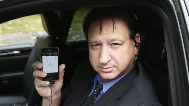 Un chofer de Uber muestra la aplicación de la compañía, mientras espera clientes en Beverly Hills, en Californie (archivos).