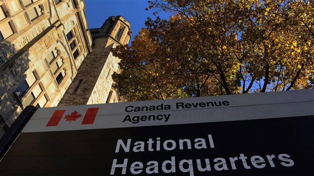 Want to contact the Canadian Revenue Agency? Try again! We see the tower of the C.R.A. headquarters sitting below a lovely, blue sky and next to a large tree with autumn foliage. In the front of the picture is a sign marked by the Canadian flag and the words "Canadian Revenue Agency, National Headquarters.