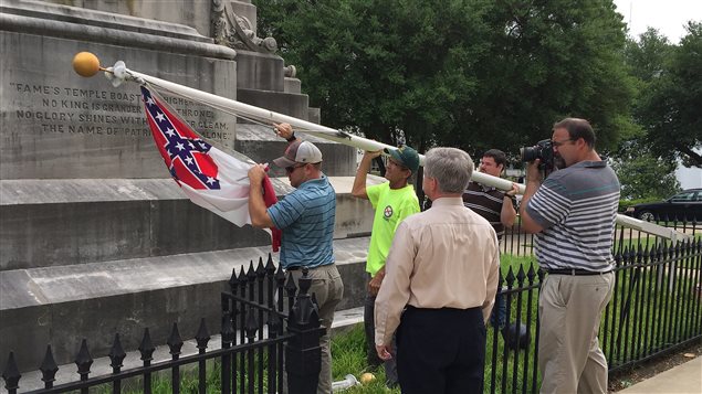 Des travailleurs municipaux de Montgomery descendent le drapeau confédéré qui flottait devant le Capitole de l'Alabama.