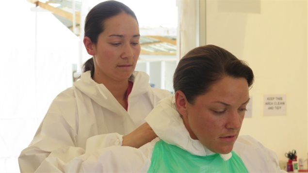 Lt.-Cmdr. Melanie Espina, lead doctor of Canada’s Operation Sirona, ties protective clothing on medic Master Cpl. Nanette Black in January 2015  just before the two enter the Kerry Town Ebola treatment unit in  Sierra Leone. 