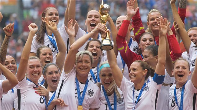 The United States Women's National Team celebrates after beating Japan 5-2 in the FIFA Women's World Cup soccer championship in Vancouver on Sunday. We see the girls (about six abreast in two rows) wearing glorious smiles as they hold the trophy aloft.