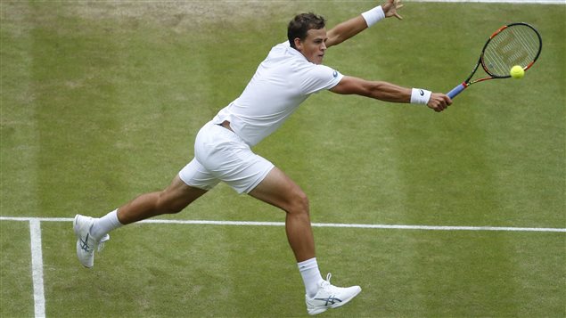 Vasek Pospisil came up just a tad short against world No. 3 Andy Murray in the Wimbledon quarter-finals on Wednesday. We see Pospisil just inside the service line reaching wide for a backhand. He is above the green turf with both hands extended.
