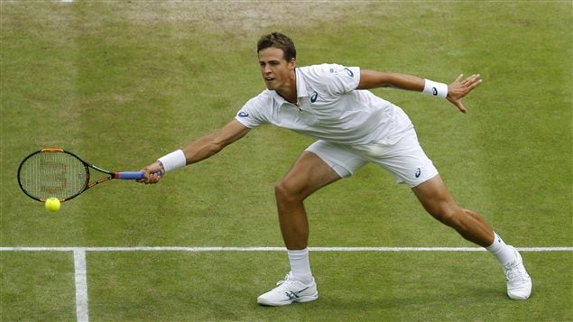 Doctors have told Vasek Pospisil to tone things down for the next two to three weeks. We see Pospisil reaching for a forehand at Wimbledon. He is just inside the ad-court service line. His left hand is extended behind him, his right hand is reaching for the volley which is at thigh level. He is, of course, dressed all in white and wears a white wrist band on his hitting arm.