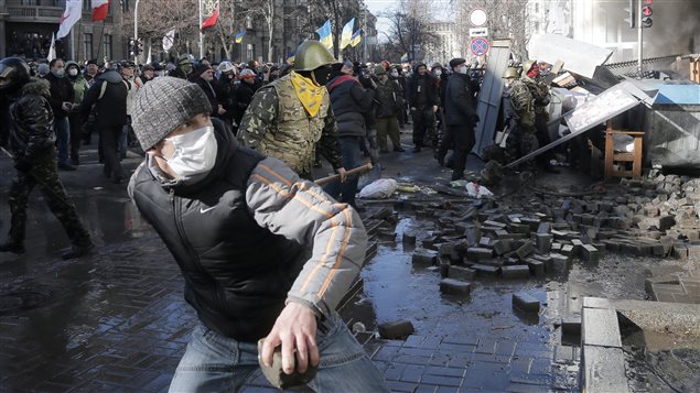 Des manifestants lancent des pavés à des policiers anti-émeute devant le parlement ukrainien, à Kiev.Crédit photo : Efrem Lukatsky
