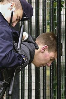 Maxime Brunerie is held by a police officer after he fired a rifle shot at then French president Jacques Chirac, who was reviewing troops during the 2002 Bastille Day parade in Paris.