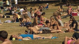 It's that most wonderful time of the year, but you best use your head when you're catching those rays. We see flocks and flocks of college people, many of them girls in bikinis of all colours, taking in the sun on the green grass of a sunny park in Vancouver.