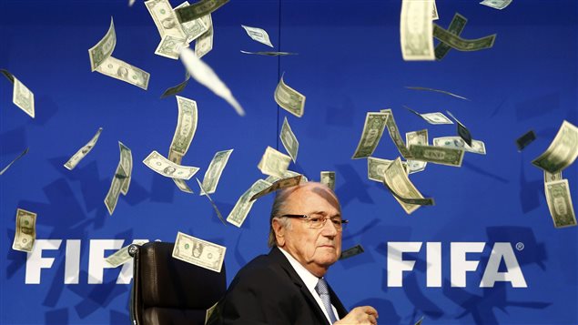 Sepp Blatter, presidente de la FIFA, bajo una lluvia de billetes falsos lanzados por un comediante británico como acto de denuncia de corrupción en ese organismo internacional.