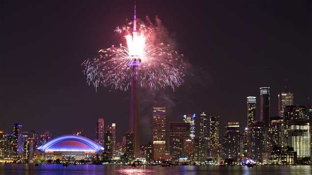  Fireworks explode from the CN Tower over downtown Toronto during the closing ceremonies of the Pan Am Games on Sunday. Will there be a repeat performance for the 2024 Olympics? We see a beautiful shot of the city from across the water. The fireworks are red and white, towering above the blue-lit Rogers Centre. All the colours are reflected in waters of Lake Ontario. To the right, we see the tall buildings of downtown Toronto.