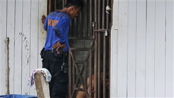 In this photo from Nov. 2014, a security guard talks to detainees in a cell at a fishing company in Benjina, Indonesia. 