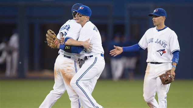 New Jays shortstop Troy Tulowitzki, centre, celebrates with teammates Josh Donaldson, left, and Ryan Goins--the core of what many believe is the best defensive infield in baseball--after a win over Philadelphia last week. We see Tulowitzki hugging Donaldson while Goins lags just a touch behind, offering his hand for a shake. All are in the Jays's milk-white home uniform with the blue cap and double blue strips down the pant leg.