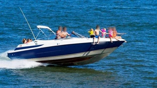 The photo shows five children sitting on the bow of moving speedboat. At least one is not wearing a life jacket.