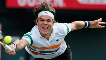 Milos Raonic enters the Rogers Cup seeded eighth. Wearing a white shirt with horizontal yellow and blue stripes and a white headband, Raonic is coming at us with his mouth open and his racquet outstretched about to strike a volley. He is coming hard because his dark hair is flying above his head.