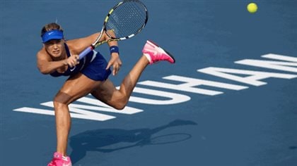 The Rogers Cup gives Genie Bouchard another opportunity to break her season-long slump. We see Genie stretched out to her right after hitting a forehand from the baseline. She is dressed in a blue tennis dress, a blue visor and pink tennis shoes. He back leg is lifted high.