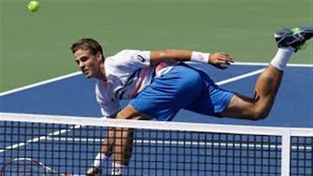 Vasek Pospisil will try to repeat his wonderful Wimbledon this week at the Rogers Cup in Montreal. Wearing a white shirt and long, blue shorts, we see Pospisil reaching to his right after hitting a volley at the net. His back (right) foot is way up in the air.