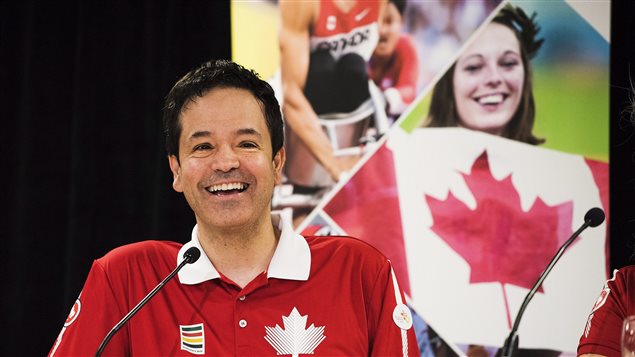 Boccia player Marco Dispaltro will serve as the flag bearer for Team Canada during a Parapan American Games opening ceremonies Friday in Toronto. We see a thin, dark-haired man wearing a red polo shirt with a white colar from  the middle of the chest up. On the left side of the shirt is a white maple leaf symbol. He has a wide smile on his face. Behind him is a poster that has a pretty young girl holding a big Canadian flag. Above her on the poster, we see a person who appears to be a track athlete.