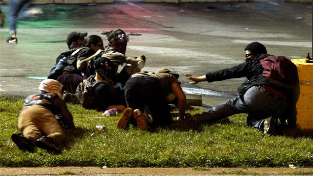 Manifestantes en Ferguson se protegen durante el tiroteo.