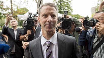 Nigel Wright, former chief of staff to Prime Minister Stephen Harper, makes his way through a crush of media as he arrives to testify at the criminal trial of embattled Senator Mike Duffy in Ottawa on Wednesday. We see Wright trying to keep a poker face in a sharp, grey suit looking ahead. Behind him are dozens of photographers.