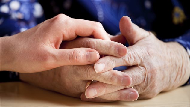 Une jeune personne tenant la main d'un aîné.