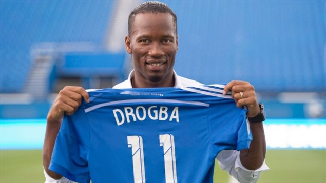 Didier Drogba, newest member of the Montreal Impact holds up his new team jersey following a news conference in Montreal, Thursday, July 30, 2015.