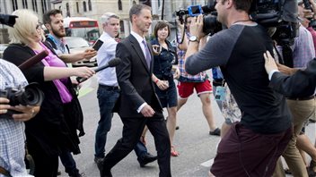Nigel Wright leaves the courthouse in Ottawa following his sixth day and last day of testimony at the trial of former senator Mike Duffy on Wednesday. We have a long shot from the side. We see Wright in full length in full stride wearing a sharp, dark suit. He is surrounded by a dozen or so reporters, cameramen and photographers using all manner of tools--from cameras to smart phones to microphones. The media are a disparate group of men and women, dressed in everything from dresses to shorts.