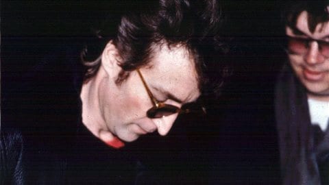 John Lennon autographie un album pour Mark David Chapman (à droite), à la sortie de son appartement de New York le 8 décembre 1980.