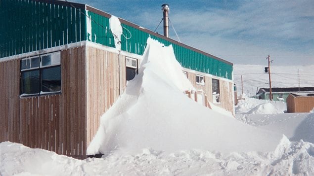 Snow piled up against a building blocking the doorway and stairs; One of the considerations of the new design was attention to aerodynamics to avoid the accumulation of snow blocking access