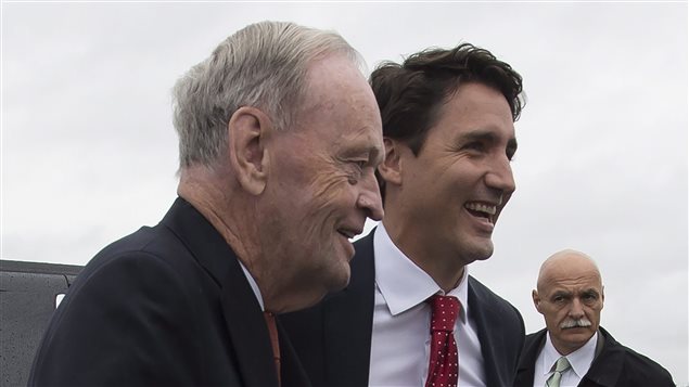 We see Chretien, greying, slightly hunched, and smiling, next to Trudeau, who is flashing a wide smile and appears very confident under his styled dark hair.